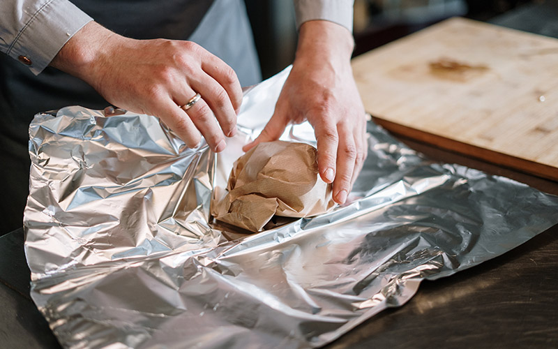 a person wrapping an item in aluminum foil