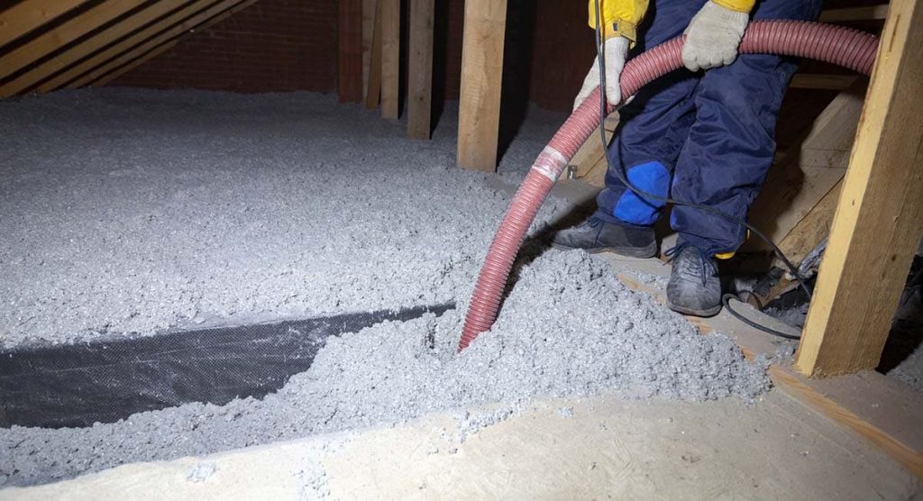 Spraying cellulose insulation in the attic of a house.