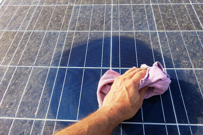 cleaning a dirty surface of a solar panel with a wet towel