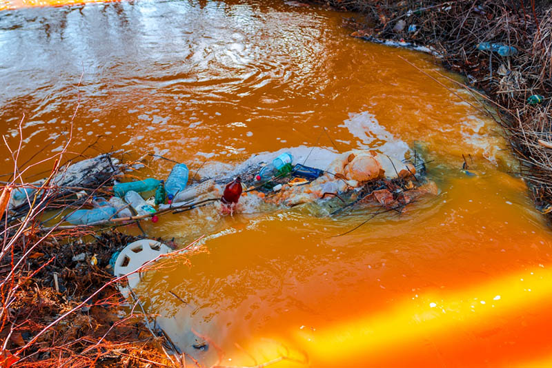 orange color river water with plastic trash
