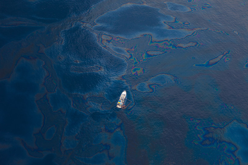 a ship floats amongst a sea of spilled oil