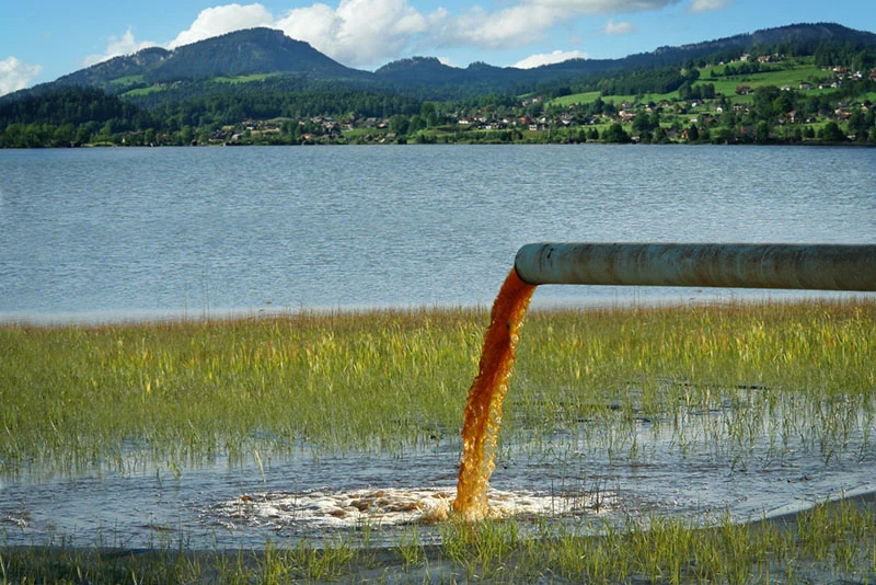 dirty water from an industrial pipe flowing into a lake