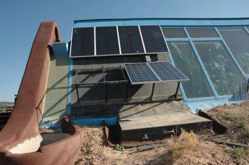 earthship house with large windows and solar PV panels