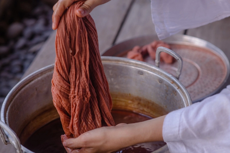 a person dyeing a piece of fabric in a bucket with water
