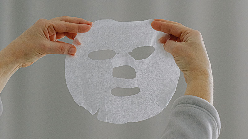 a woman holding a face sheet mask