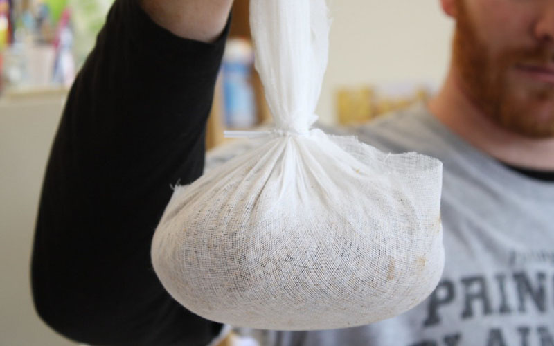 man holding cheesecloth with food wrapped in ut