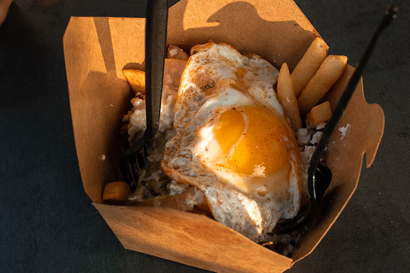 fries and fried egg in a paper food container