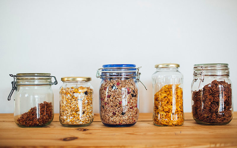 five glass jars with food on a wooden table