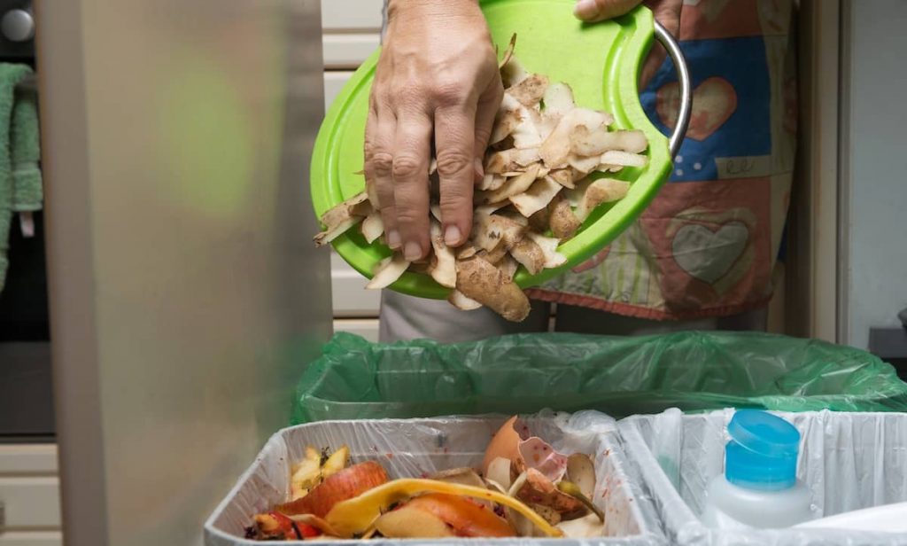 a person throwing away vegetable scraps