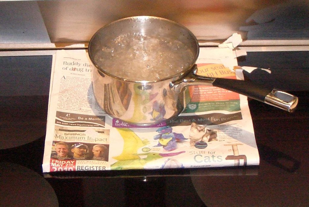 Water boiling on an induction stove with newspaper in-between the pan and the stove