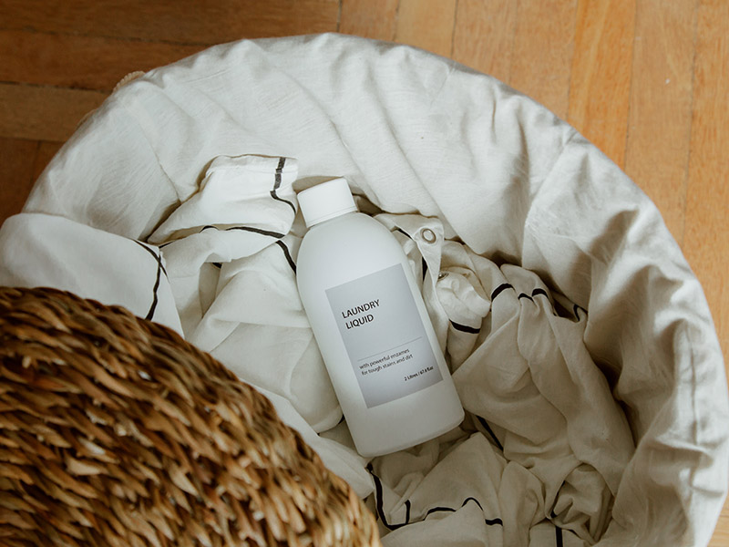 laundry detergent bottle in a basket with sheets