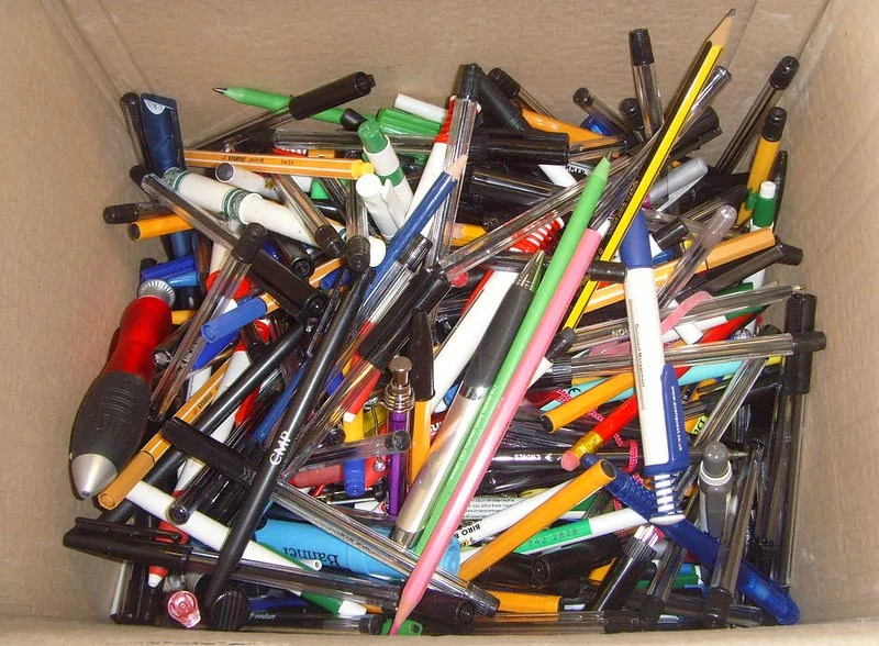 old pens and pencils in a cardboard box