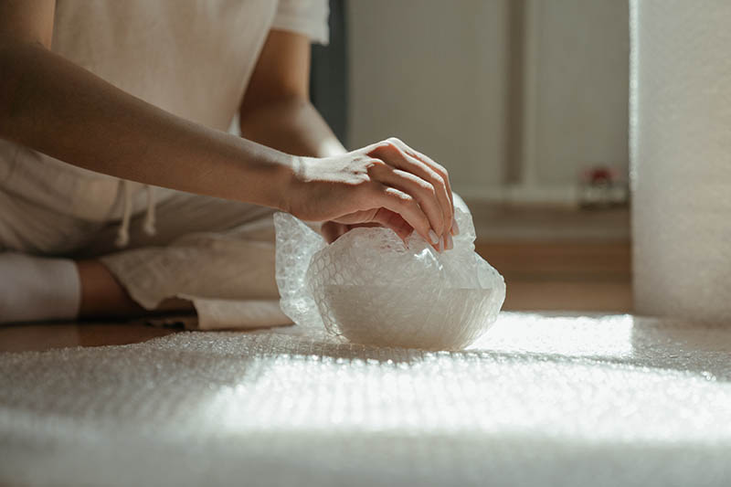 a person wrapping a bowl into a bubble wrap