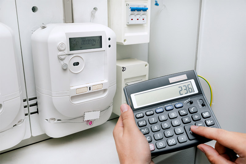 a person holding a calculator next to an electricity meter