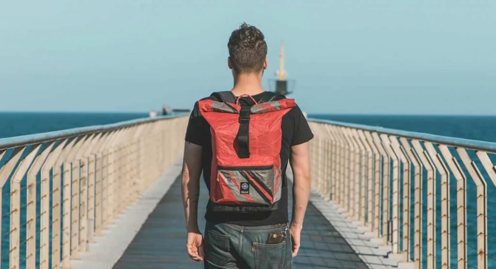 a man wearing travel backpack made of recycled kitesurfing sails