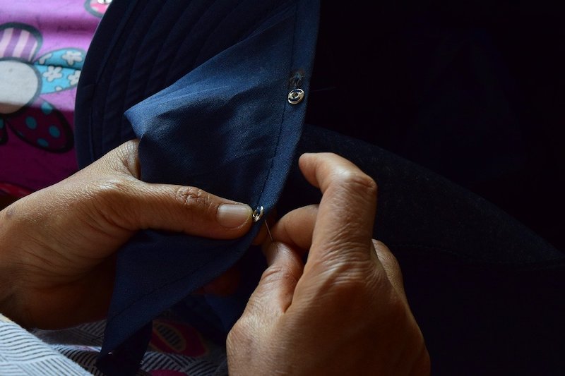 a woman sewing in a clothing rivet on a shirt