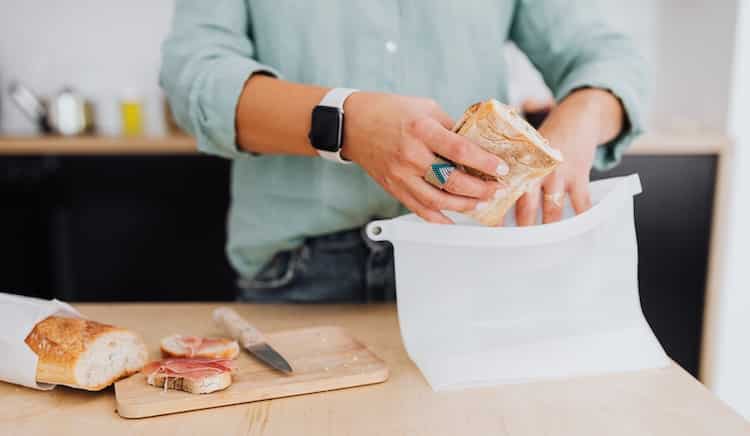 woman packing bread into a silicone storage bag