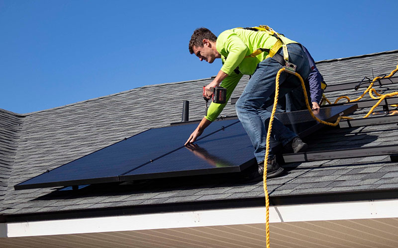 a male worker installing solar panels on the roof
