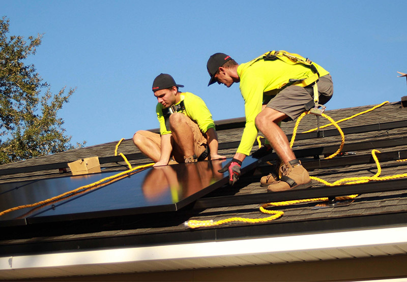 solar company workers installing solar panels on a roof