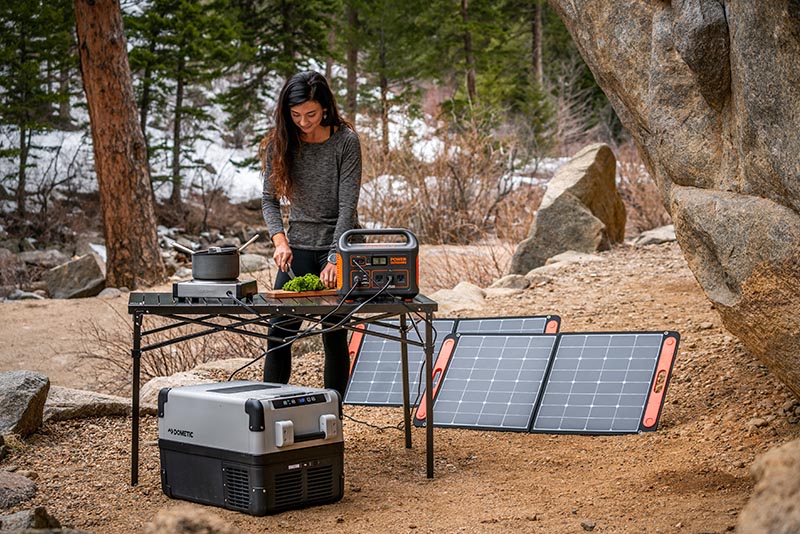 woman cooking a meal using a stove powered by a portable solar panel