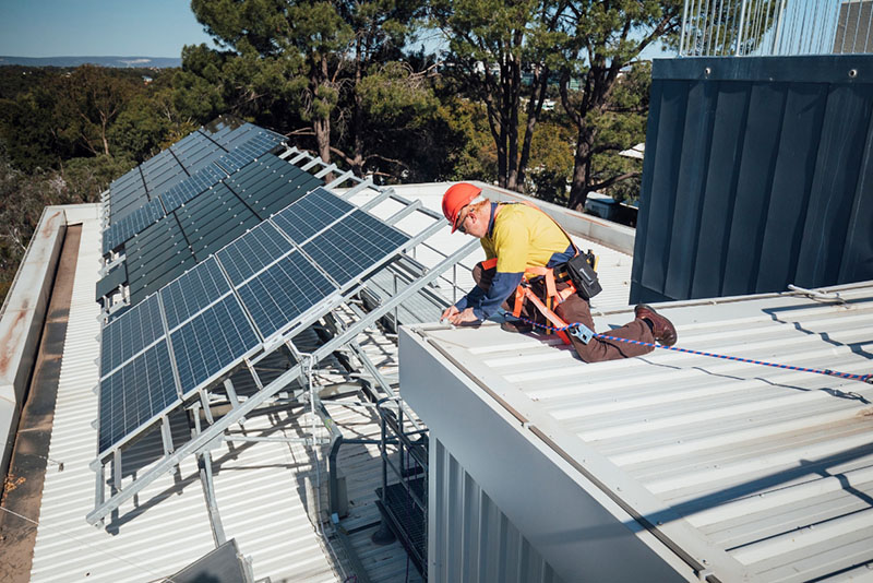 solar panel installer repairing solar panel on an industrial building roof