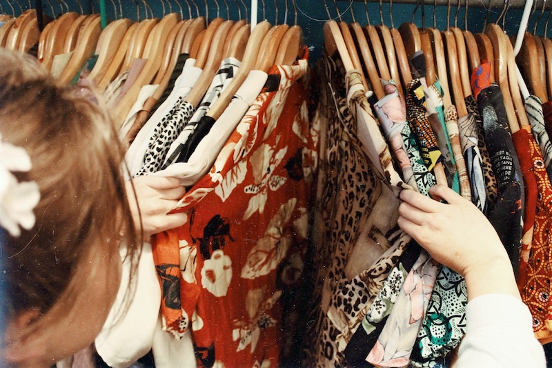 a woman looking through the old clothing pieces on hangers
