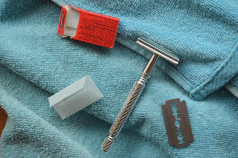 a double edge safety razor with a razor blade on a blue towel