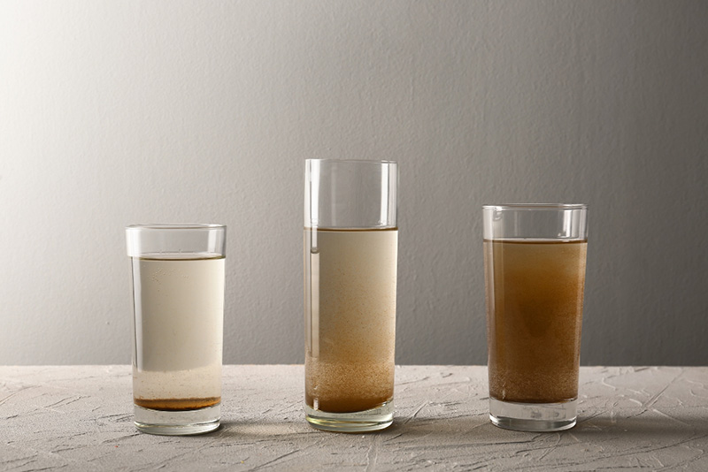 three glasses with dirty water on a table