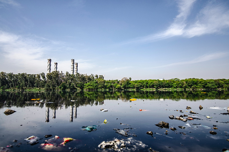 polluted body of water with a factory in the background
